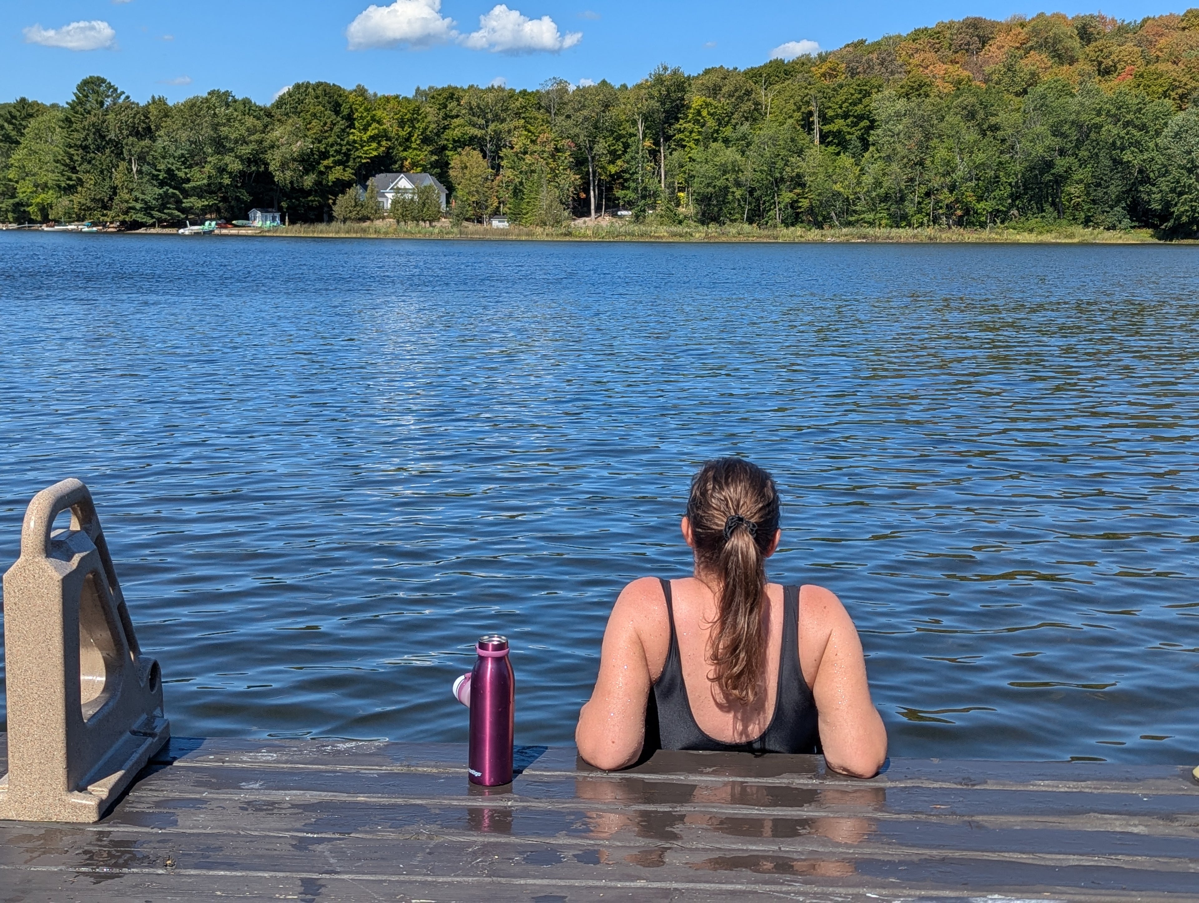 Woman standing on The Dock Ledge in-water platform, looking out at a beautiful lake.