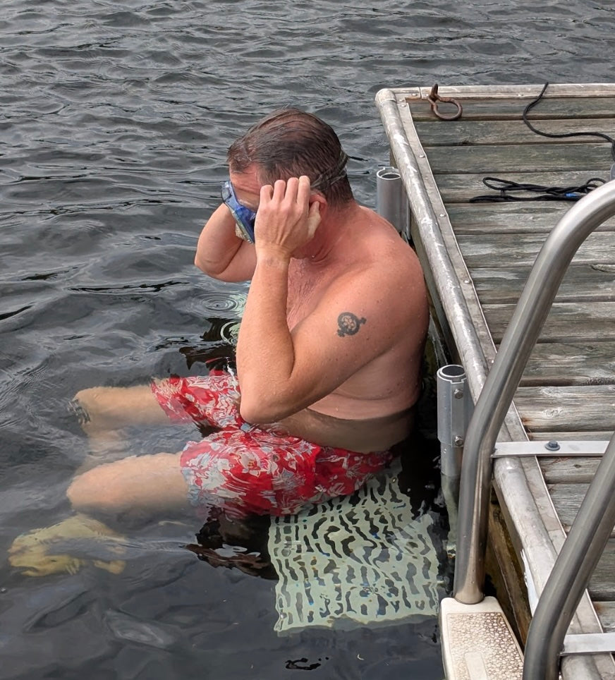 The Dock Ledge in-water platform can be adjusted to different heights. In this image, we see a person sitting on The Dock Ledge getting ready to go snorkelling.