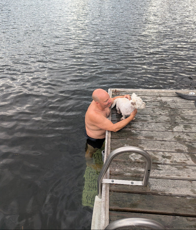 Man standing on The Dock Ledge having a quick cuddle with his dog.